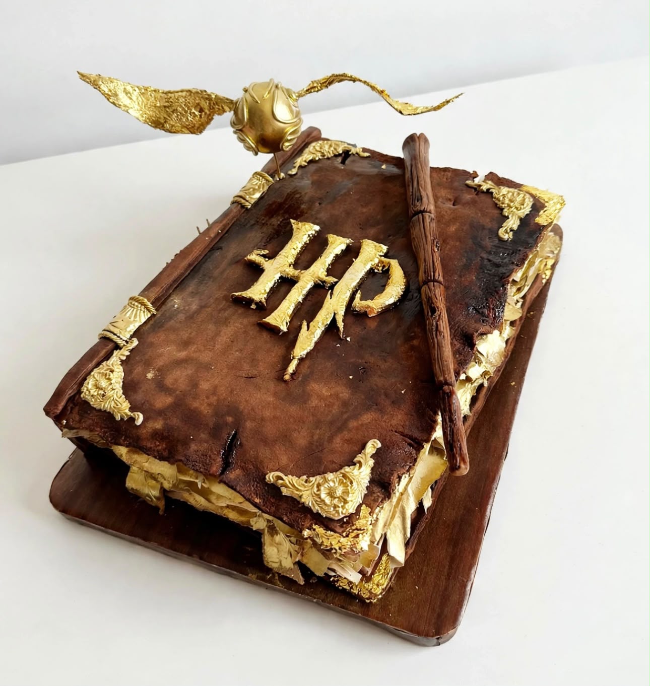 Pastel esculpido con forma de libro antiguo de magia con detalles dorados