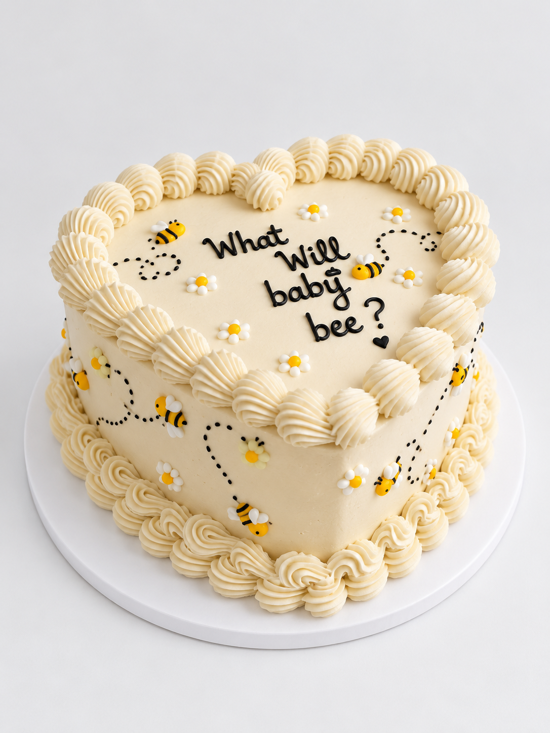 Pastel en forma de corazón decorado con abejitas de azúcar y el mensaje What Will baby bee